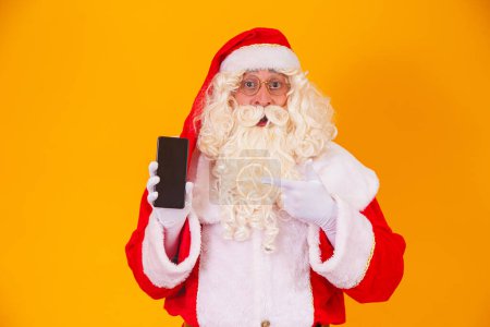 Photo for Santa Claus holding a smartphone in hands - Royalty Free Image