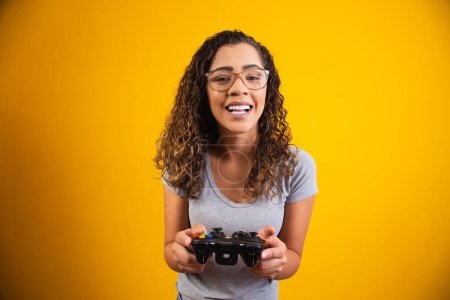 Foto de Mujer emocionada jugando videojuego sobre fondo amarillo. - Imagen libre de derechos