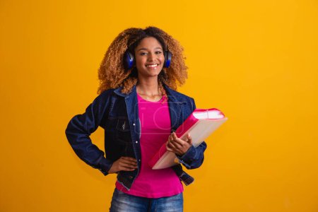 Photo for Young afro student with books on yellow background. - Royalty Free Image