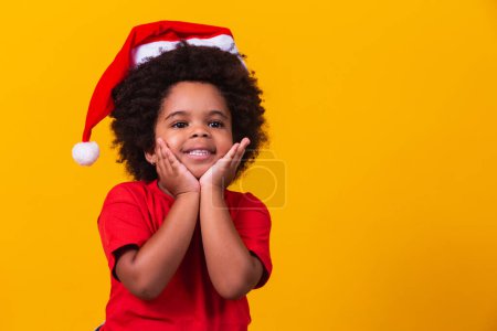 Téléchargez les photos : Adorable petite afro girl en t-shirt rouge et chapeau de Père Noël habillé pour Noël avec espace pour le texte - en image libre de droit