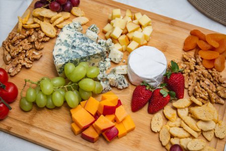 Photo for Cheese plate with variety of appetizers on table. Strawberry, apricot, grape and grain cheese dishes on the table - Royalty Free Image