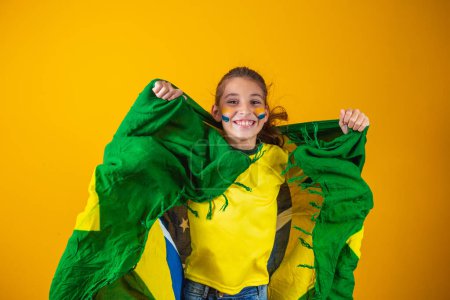 Foto de Amante del fútbol, equipo de Brasil. Hermosa niña animando a su equipo sobre fondo amarillo - Imagen libre de derechos