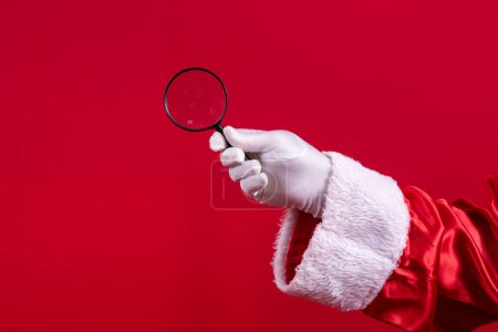 Photo for Close-up of Santa's gloved hand holding a magnifying glass. - Royalty Free Image