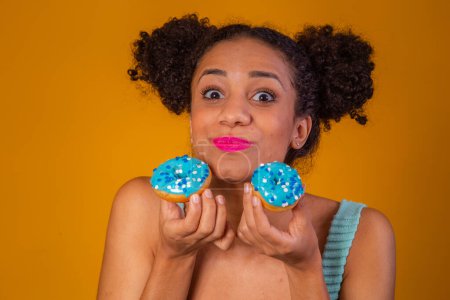 Photo for Cute afro girl holding two colorful donuts. Afro woman with donuts - Royalty Free Image