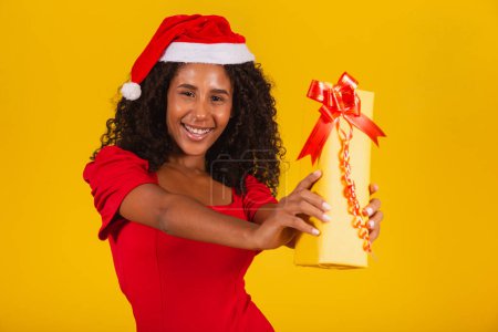 Photo for Young afro girl holding an expressive Christmas present. - Royalty Free Image