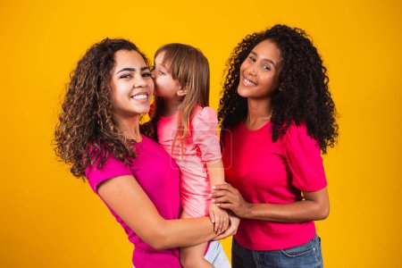 Photo for Happy lesbian couple with little adopted girl on color background - Royalty Free Image