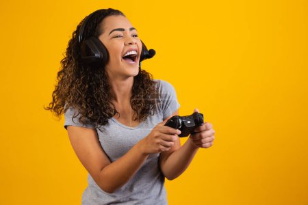 Photo for Excited woman playing video game on yellow background. - Royalty Free Image