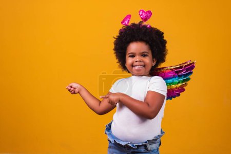 Téléchargez les photos : Adorable afro girl habillée en tenue colorée sur fond jaune. Journée de l'enfant. afro fille avec costume - en image libre de droit