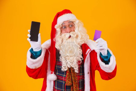 Téléchargez les photos : Père Noël utilisant la carte de crédit pour payer les achats sur Internet - en image libre de droit
