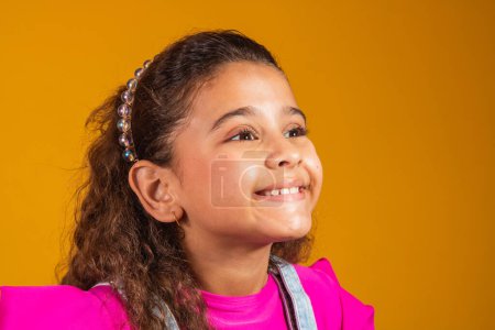 Foto de Primer plano de chica mixta sonriendo sobre fondo amarillo. Chica de raza mixta con el pelo ondulado feliz. Día de los Niños - Imagen libre de derechos