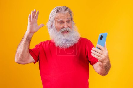Photo for Cheerful elderly man holding a smartphone, having video call online, chatting with grown children, communicating with a friend at a distance, older generation modern technology comfortable user-friendly concept. - Royalty Free Image