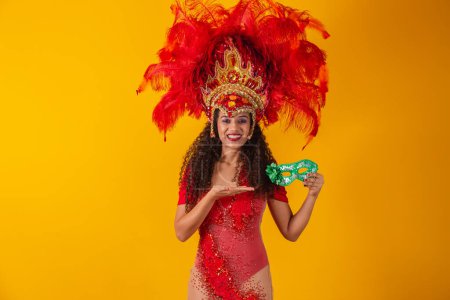 Photo for Young afro woman in samba and carnival outfit holding a green mask smiling at the camera. - Royalty Free Image
