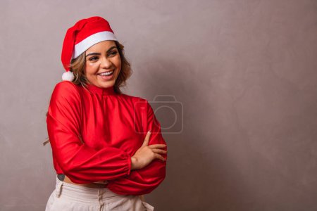 Foto de Primer plano de una hermosa joven con el sombrero de Santa y los brazos cruzados. Feliz Navidad. - Imagen libre de derechos