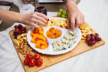 Téléchargez les photos : Assiette au fromage avec une variété d'entrées sur la table. Plats aux fraises, abricots, raisins et fromages à grains sur la table - en image libre de droit