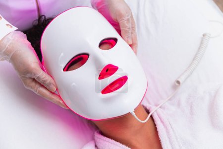 Téléchargez les photos : Masque facial thérapie photodynamique sur le visage de la femme - en image libre de droit