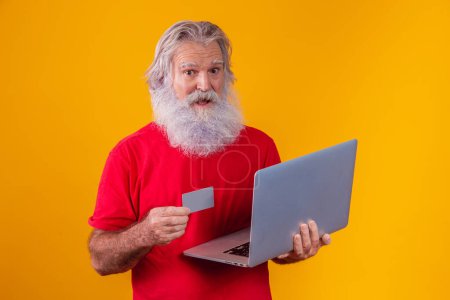 Photo for Elderly man holding laptop computer and bank credit card. Online shopping transaction. Mobile banking cashless method. - Royalty Free Image