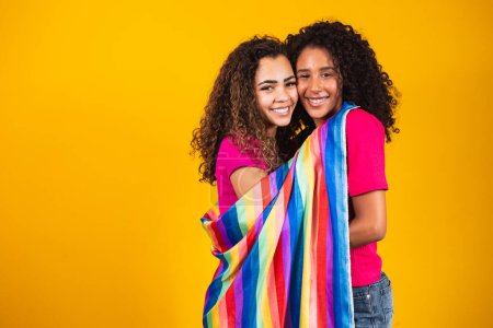 Photo for Couple lesbian woman with gay pride flag in yellow background - Royalty Free Image