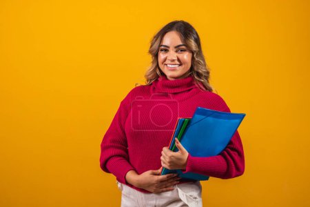 Photo for Smiling plus size woman student with school books in hands on yellow background. - Royalty Free Image