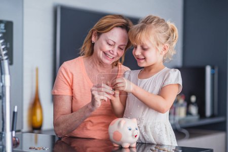 Photo for Close up happy older mother and adorable little daughter holding touching pink piggy bank, caring mum and adorable girl child saving money for future, family insurance and investment concept - Royalty Free Image