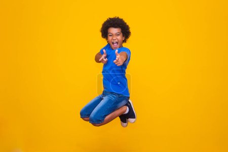 Photo for Little afro boy jumping on yellow background. - Royalty Free Image