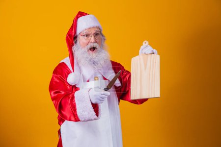 Foto de Santa Claus vestido con delantal sosteniendo plato de carne vacía y cuchillo - Imagen libre de derechos