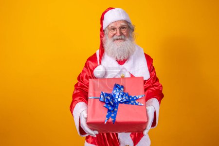 Photo for Santa Claus holding a gift box on yellow background. Christmas and New Year concept - Royalty Free Image