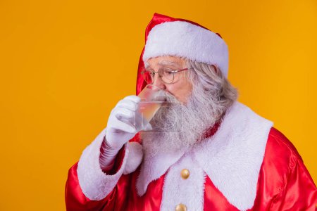 Foto de Santa Claus bebiendo un vaso de agua sobre fondo amarillo con espacio para el texto. Concepto de salud e hidratación - Imagen libre de derechos