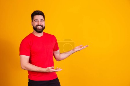 Photo for Handsome man with beard pointing to the side smiling looking at the camera. - Royalty Free Image