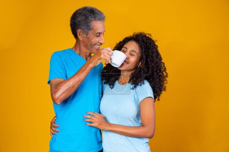 Téléchargez les photos : Père avec une tasse de café passant près du nez de sa fille pour qu'elle sente l'arôme. Photo pour le café et la fête des pères campagnes - en image libre de droit