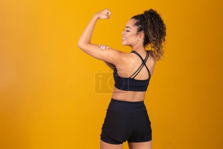 Téléchargez les photos : Jeune femme sportive montrant les muscles du dos et les biceps - en image libre de droit