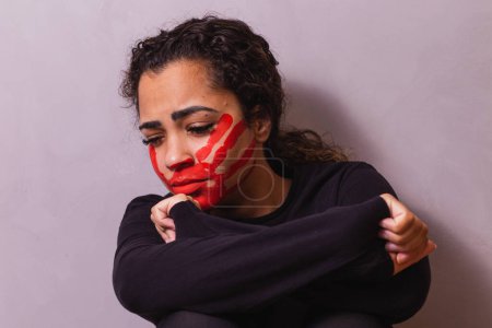 Téléchargez les photos : Femme avec une empreinte sur la bouche, démontrant de la violence sur les femmes. Femme protestant contre la violence domestique et les abus en arrière-plan. - en image libre de droit