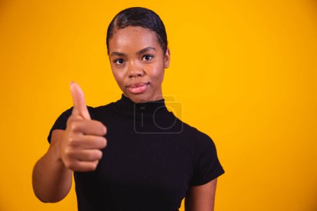 Photo for Black  woman over yellow wall giving a thumbs up gesture because something good has happened - Royalty Free Image
