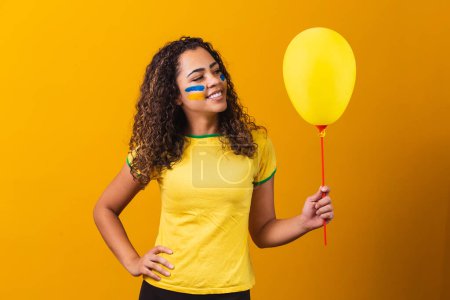 Téléchargez les photos : Ventilateur brésilien tenant un ballon jaune avec espace libre pour le texte. Brésil promotion du jeu - en image libre de droit