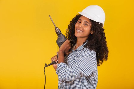 Téléchargez les photos : Entrepreneur femme avec une perceuse sur fond jaune. - en image libre de droit