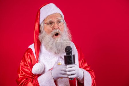 Téléchargez les photos : Père Noël chantant ou parlant dans un microphone de studio. Joyeux Noël. Diffuseur. Annonceur. Promotion. Concept de musique de Noël - en image libre de droit