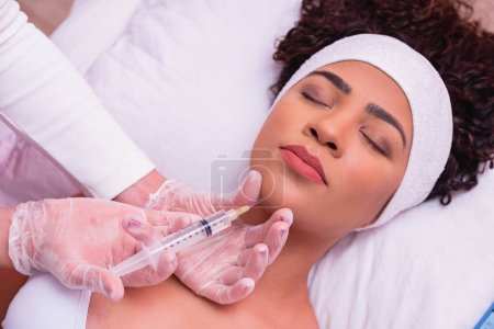 Photo for Pretty girl getting hyaluronic acid treatment. Attractive young woman is getting a rejuvenating facial injections. - Royalty Free Image
