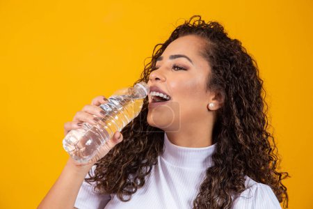 Foto de Mujer joven y saludable bebiendo agua sobre fondo amarillo con espacio para el texto. - Imagen libre de derechos