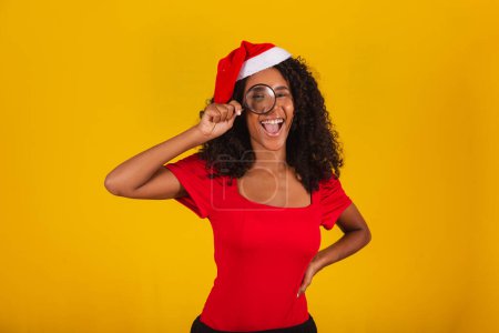 Foto de Mujer vestida para Navidad en sombrero de santa usando una lupa - Imagen libre de derechos