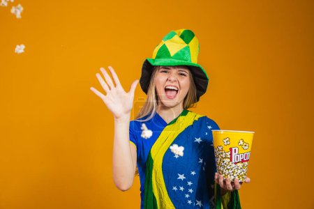 Photo for Brazilian fan with popcorn to watch the game. Entertainment, sport and patriotism concept - Royalty Free Image