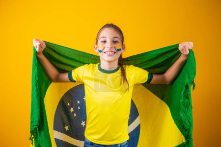 Foto de Amante del fútbol, equipo de Brasil. Hermosa niña animando a su equipo sobre fondo amarillo - Imagen libre de derechos