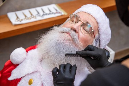 Photo for Santa Claus shaving in barbershop. Getting ready for Christmas. Beautifying for the holidays. Bearded. Cuting. - Royalty Free Image