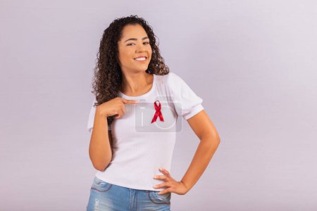 Foto de Mujer joven con lazo rojo en camiseta para la campaña de prevención del VIH. Señalando - Imagen libre de derechos