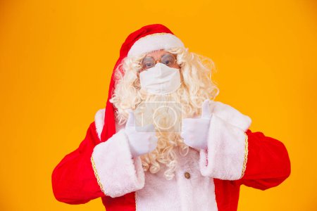 Foto de Real Santa Claus sobre fondo amarillo, con máscara protectora contra el cóvido19. Navidad con distancia social. Covid-19 - Imagen libre de derechos
