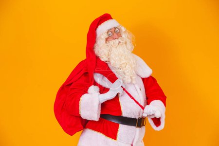 Foto de Santa Claus con una bolsa enorme en la prisa para entregar regalos de Navidad. Santa Claus sobre fondo amarillo - Imagen libre de derechos