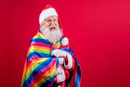 Téléchargez les photos : Le Père Noël couvre de drapeau de fierté LGBT. Tout seul. Un seul. Garder le poing levé, couvrir le drapeau LGBT. Drapeau LGBT + sur fond rouge. Noël !. - en image libre de droit