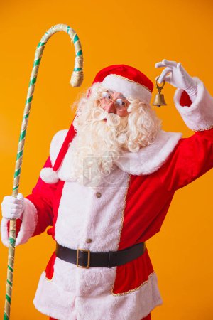 Téléchargez les photos : Père Noël avec cloche sur fond jaune. beau Père Noël - en image libre de droit