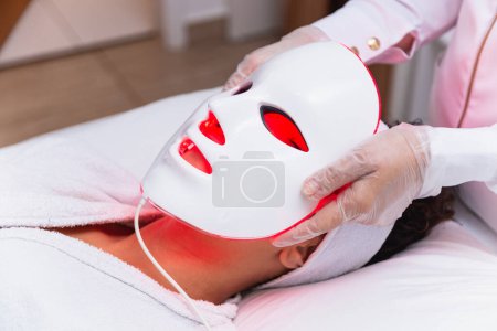 Téléchargez les photos : Masque facial thérapie photodynamique sur le visage de la femme - en image libre de droit