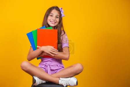Photo for Little student girl with notebooks in hands sitting - Royalty Free Image