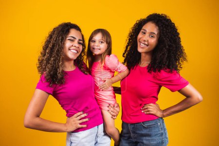Photo for Happy lesbian couple with little adopted girl on color background - Royalty Free Image