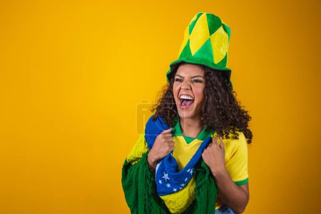 Photo for Brazil supporter. Brazilian curly hair woman fan celebrating on soccer, football match on yellow background. Brazil colors. - Royalty Free Image